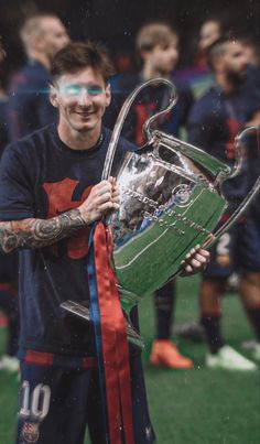 a man holding a soccer trophy on top of a field