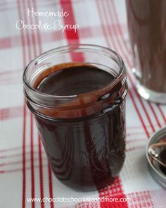 homemade chocolate syrup in a glass jar on a red and white checkered tablecloth