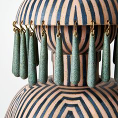 several green earrings hanging from the top of a large vase with gold chains attached to them