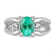 an oval emerald and diamond ring with three diamonds on the band, set in white gold