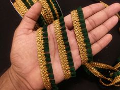 a hand holding some green and gold ribbon in it's palm with two hands