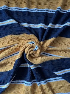 a blue, yellow and white striped blanket laying on top of a bed