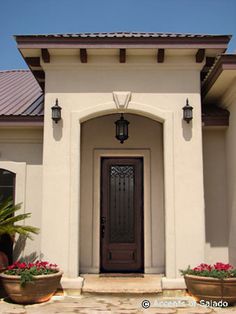 a house with potted plants in front of it and a door on the side