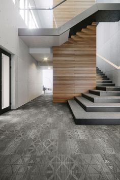 the stairs in this modern building are made out of wood and concrete, while carpet is laid on the floor