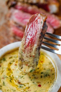 a piece of meat sticking out of a bowl of soup with a fork in it