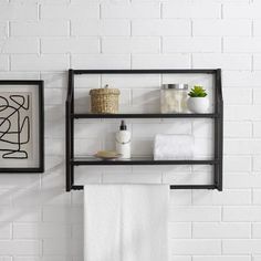 two black shelves with towels and other items on them against a white brick wall in a bathroom