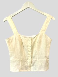 Washed Luxe European Handkerchief Linen in Creme. Fitted top with wide straps and snap front closure. The princess seams give shape to this little peplum vest type top. Great layering piece. Two Variations: Embroidered Back detail: Adorned with embroidered flower applique and ruffled bustle. Simplicity. Other colors available. Made in small batches. Allow 2 - 3 weeks for delivery when out of stock. White Linen Square Neck Top, Cropped Vest With Button Closure For Summer, Summer Cropped Vest With Buttons, Cropped Summer Vest With Buttons, Fitted Top With Adjustable Straps For Daywear, Fitted Ruffled Tank Top For Daywear, Fitted Ruffle Tank Top For Daywear, Fitted Linen Tops With Buttons, Fitted Linen Top In Beige