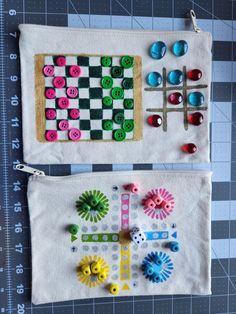 two pieces of fabric with buttons and pins on them sitting next to each other in front of a ruler