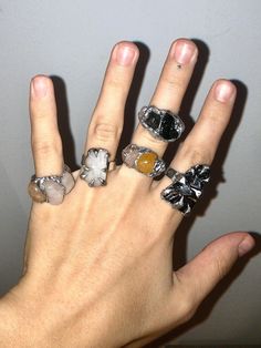 a person's hand with five different rings on it, including one for the middle finger