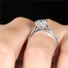 a close up of a person's hand with a diamond ring on their finger