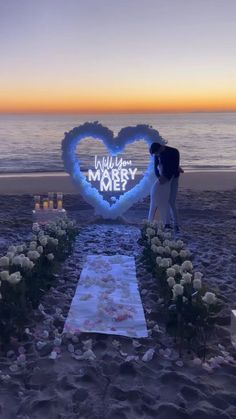 a wedding setup on the beach with flowers and candles in the shape of a heart