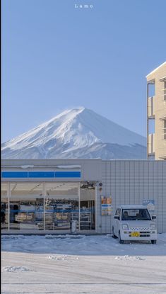 a white van parked in front of a building with snow on the ground and a mountain behind it