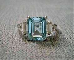 an aqua and white topaz ring with three baguets on the side, set in