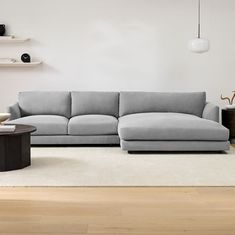 a living room with a gray couch and coffee table in front of the sofa is a white rug