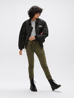 a woman in black jacket and green pants