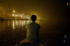 a man sitting on a boat in the water at night