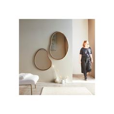 a woman standing next to a mirror in a room with white walls and flooring