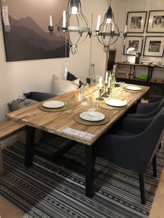 a dining room table set with place settings and plates on it, in front of a couch