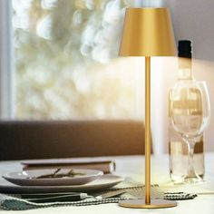 a lamp that is on top of a table next to a plate and wine glass