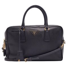 Introducing the Prada shoulder bag constructed from black saffiano lux leather. The bag features gold-tone hardware, dual rolled leather top handles and protective feet at the base. The top zip opens to a logo jacquard lining with a single interior pocket. Category, retail. Color: Black Material: Saffiano leather Made in Italy Measurements~ Height 8.5” Width 13” Depth 3.5” Handle drop: 7” Comes with a shoulder strap. Good condition. Bag was refurbished by a leather repair professional. Stains an Prada Shoulder Bag, Leather Repair, Prada Saffiano, Miuccia Prada, Chanel Vintage, Shoulder Bag Black, Boston Bag, Flap Bag, Bag Shoulder