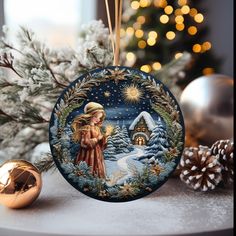 a christmas ornament hanging on a table next to a pine tree and gold ornaments