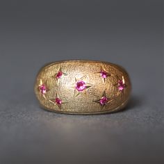 An eye catching and finely crafted vintage bombe ring dating to the mid-20th century. The ring has a domed profile and is set with 7 Swiss cut spinels with a deep pink hue. Each gem is held in a star setting, with a band of 14ct yellow gold and stippled detailing. A real statement piece that embodies retro glamour.  No stamps are present but the gold tests as a minimum of 14ct. Size K (US 5.5). Can be resized within reason. Weight (approximate): 2.8g Measurements (approximate): Ring measures 11m Vintage 14k Gold Domed Dome Ring, Vintage Pink Ruby Ring In 14k Gold, Bombe Ring, Star Setting, Retro Glamour, Dome Ring, Deep Pink, Domed Ring, Rings Statement