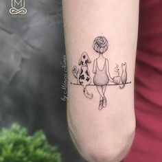 a woman sitting on a branch with her cat and dog tattoo design on the arm