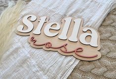 a wooden sign that says stella on it's side, sitting on top of a blanket