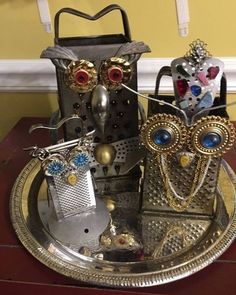 two metal owls sitting on top of a silver plate next to an empty bottle opener