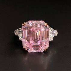 a fancy pink diamond ring on a black surface