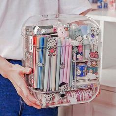 a person holding a clear container filled with pens and pencils