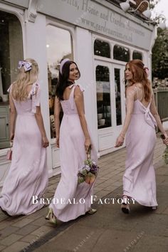 three bridesmaids in pink dresses walking down the street with flowers in their hair