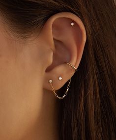 a close up of a person wearing ear piercings with chain and pearls on them