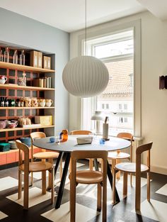 a dining room table and chairs in front of a bookshelf filled with shelves