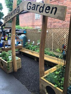 an outdoor garden area with raised wooden planters and plants growing on the sides of it