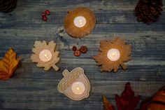 three candles sitting on top of a wooden table next to leaves and acorns