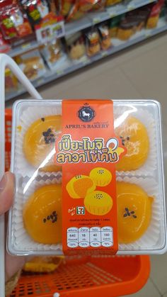 a person holding an orange in a carton at a grocery store with the package on it's side