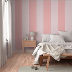 a bedroom with pink and white stripes on the wall, wooden flooring and bed