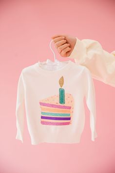 a person holding a sweater with a cake on it and a candle in the middle