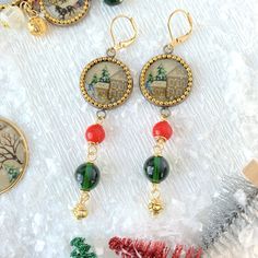 "Nostalgic holiday earrings with petite red, green and gold beads dangling from a vintage wintery cozy cabin print decoupaged under a glass lens and set in a bezel cup in an antique bronze finish. Extremely lightweight! An alluring pair of beaded holiday dangle earrings that add that final touch to your holiday outfit. These winter earrings are part of the new 2022 cozy holiday collection called \"Home for the Holidays\" which is new to our seasonal collection of unique handmade holiday jewelry. Thanks for looking! ~Dainty dangle 3-Inch drop with gold-plated, nickel-free lever-back ear wires ~Make it a set with the Home for the Holidays necklace, locket or bracelet." Handmade Vintage Jewelry For Holidays, Vintage Handmade Holiday Jewelry, Handmade Holiday Jewelry, Holiday Beading, Holiday Necklace, Winter Earrings, Holiday Earrings, Cozy Holiday, Home For The Holidays