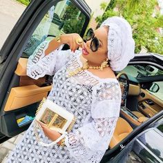 a woman in a white lace dress is leaning out the car window