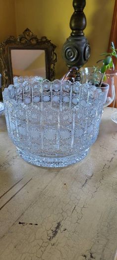 a glass bowl sitting on top of a wooden table next to a vase and mirror