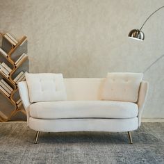 a white couch sitting in front of a tall book shelf on top of a carpeted floor