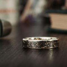 a close up of a wedding ring on a wooden table with books in the background