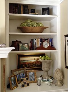 a bookshelf with pictures and other items on the shelves in front of it