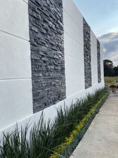 the side of a building with grass growing next to it and another wall in the background