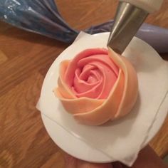 a cake with pink frosting and a knife sticking out of the center on a plate