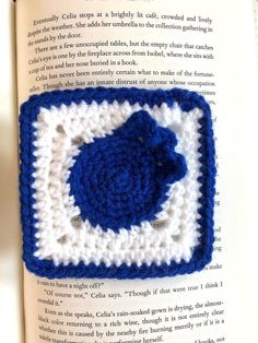 an open book with a crocheted blue and white square