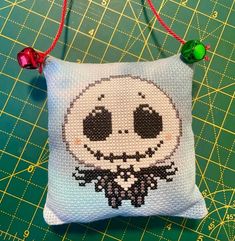 a cross stitch pillow with a jack skelling on it