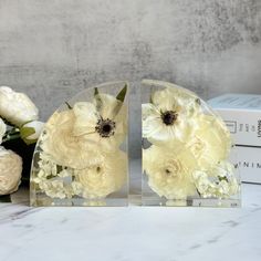 two clear vases with white flowers in them